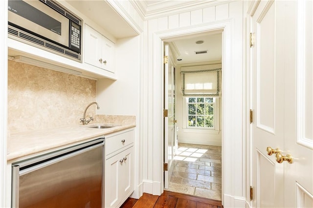 kitchen featuring visible vents, a sink, stainless steel microwave, light countertops, and dishwashing machine