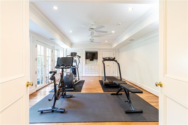 exercise room featuring a raised ceiling, wood finished floors, crown molding, and french doors