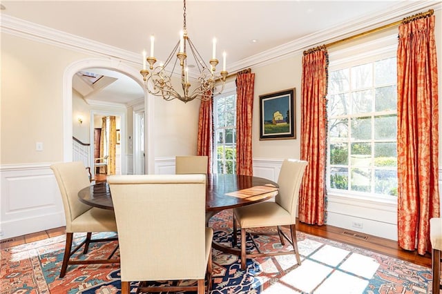 dining area featuring visible vents, plenty of natural light, light wood-style floors, arched walkways, and a notable chandelier