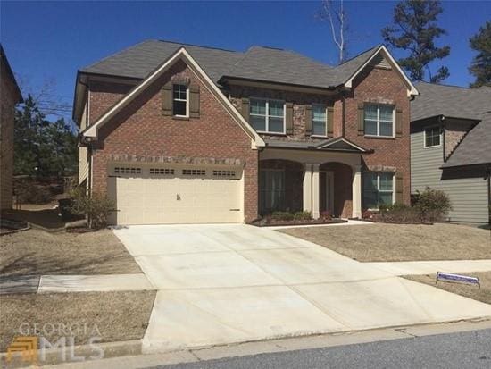 view of front of house featuring brick siding, driveway, and a garage