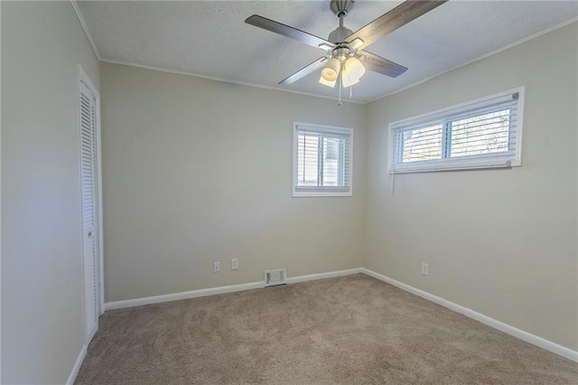 carpeted spare room with ceiling fan and ornamental molding