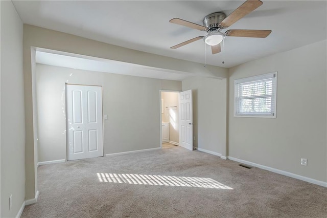 unfurnished bedroom with ceiling fan, light colored carpet, a closet, and ensuite bathroom