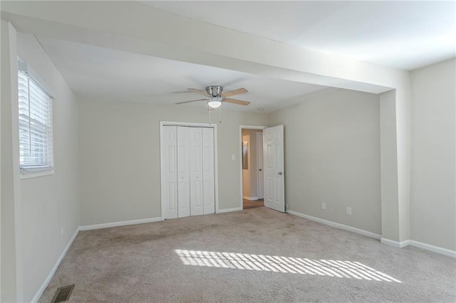 unfurnished bedroom featuring ceiling fan, light carpet, and a closet