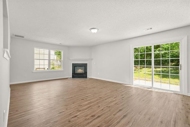 3454 Carriage Chase Rd, Atlanta, GA 30349 - unfurnished living room with wood finished floors, a textured ceiling, baseboards, and a fireplace with flush hearth