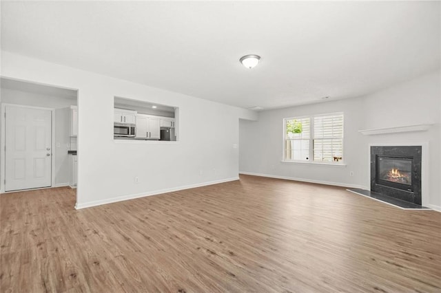 3454 Carriage Chase Rd, Atlanta, GA 30349 - unfurnished living room featuring light wood-style flooring, a high end fireplace, and baseboards