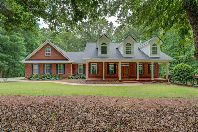 cape cod house featuring brick siding, a front yard, and covered porch