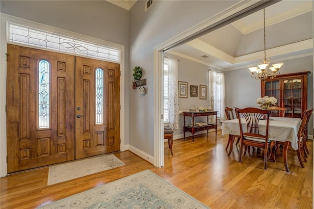 entrance foyer with a chandelier, healthy amount of natural light, light wood-style flooring, baseboards, and a towering ceiling