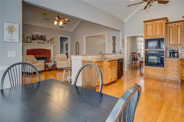 kitchen featuring black appliances, a ceiling fan, a brick fireplace, a sink, and crown molding