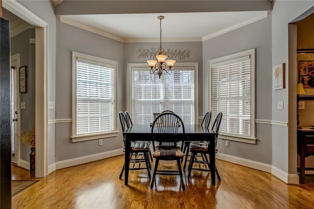 dining room with a chandelier, wood finished floors, crown molding, and baseboards