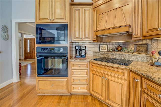 kitchen with black appliances, custom exhaust hood, backsplash, baseboards, and light wood-style flooring