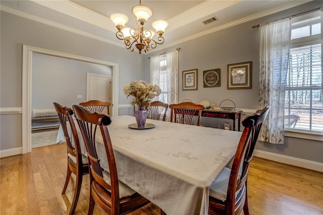dining space featuring a chandelier, healthy amount of natural light, light wood-style floors, ornamental molding, and baseboards