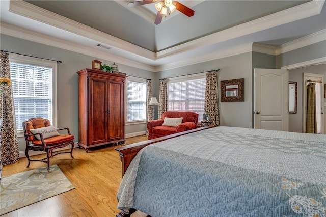 bedroom featuring crown molding, light wood-type flooring, a raised ceiling, and ceiling fan
