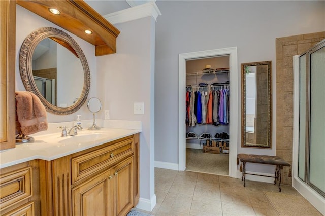 full bathroom featuring a shower stall, tile patterned flooring, a walk in closet, baseboards, and vanity