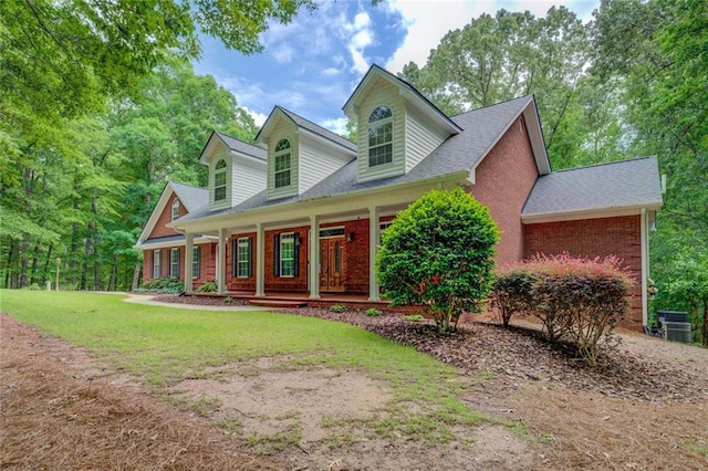 cape cod home featuring covered porch, brick siding, a front lawn, central AC unit, and roof with shingles