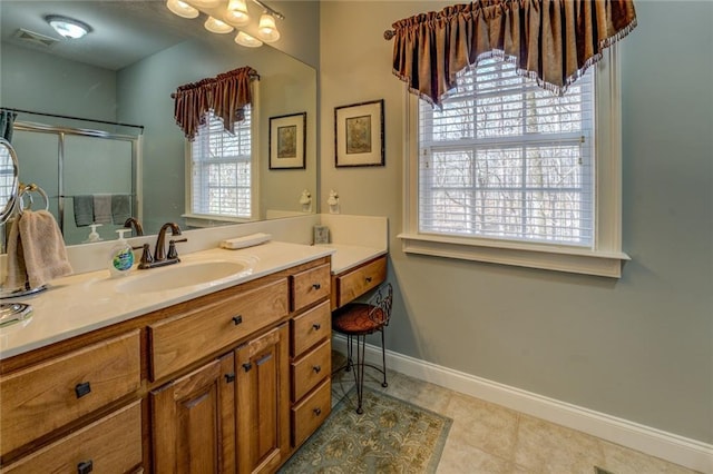 full bath featuring an enclosed shower, healthy amount of natural light, baseboards, and vanity