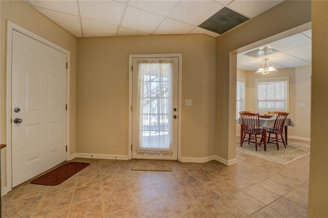 foyer with a paneled ceiling, light tile patterned floors, and baseboards