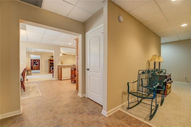 hall with a paneled ceiling, recessed lighting, baseboards, and tile patterned floors