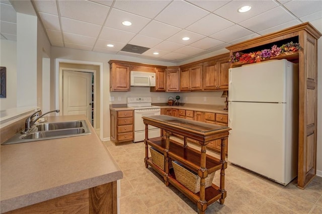 kitchen featuring white appliances, a sink, a paneled ceiling, recessed lighting, and brown cabinets