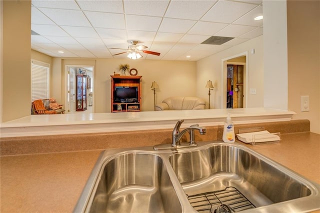 kitchen featuring a sink, a drop ceiling, a ceiling fan, and open floor plan