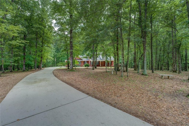 surrounding community with a wooded view and concrete driveway