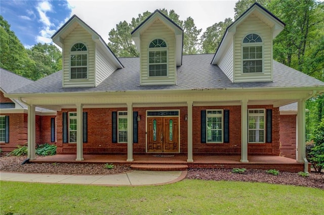 view of front of house featuring a porch, roof with shingles, brick siding, and a front lawn