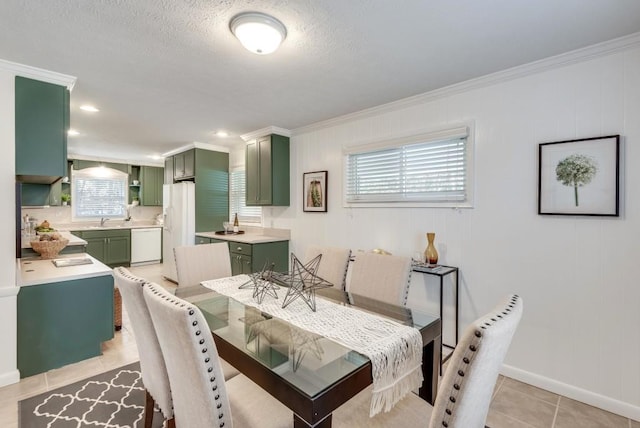 tiled dining room with a textured ceiling, ornamental molding, plenty of natural light, and sink