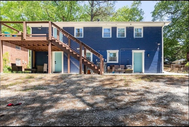 back of house with brick siding, stairway, outdoor lounge area, and a wooden deck