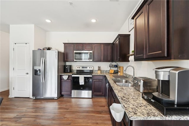 2051 Wildflower Way, Conyers, GA 30012 - kitchen with stainless steel appliances, dark brown cabinets, a sink, light stone countertops, and dark wood-style flooring