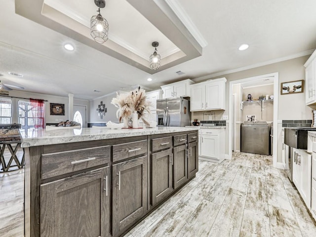 kitchen with ornamental molding, pendant lighting, white cabinets, stainless steel fridge with ice dispenser, and washer / clothes dryer