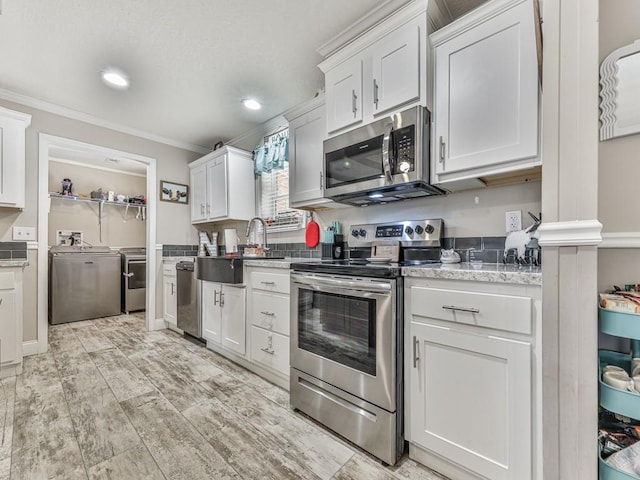 kitchen with white cabinets, crown molding, sink, independent washer and dryer, and stainless steel appliances