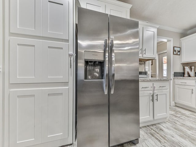 kitchen featuring light stone countertops, stainless steel fridge with ice dispenser, white cabinetry, and ornamental molding