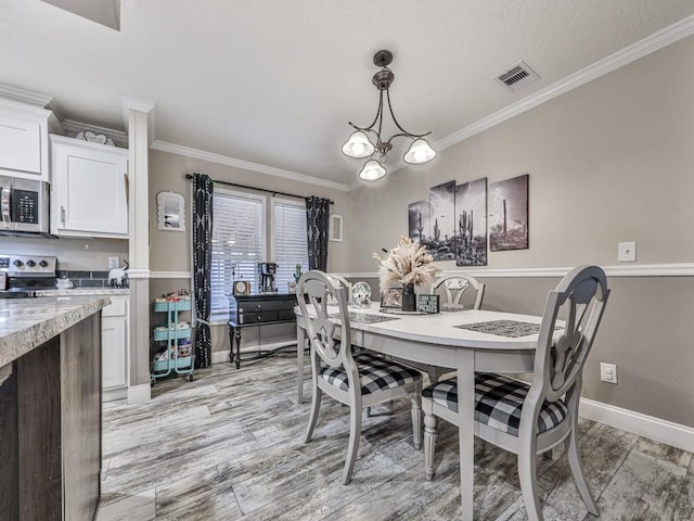 dining room with an inviting chandelier, light hardwood / wood-style flooring, and crown molding