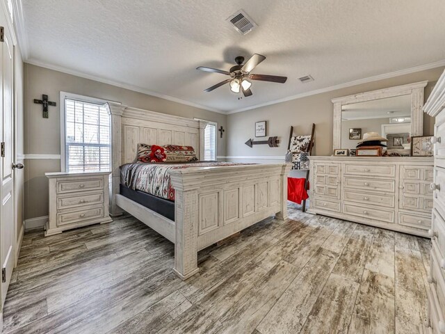 bedroom featuring hardwood / wood-style floors, a textured ceiling, ceiling fan, and ornamental molding