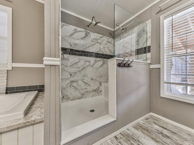 bathroom with a tile shower, crown molding, and a textured ceiling