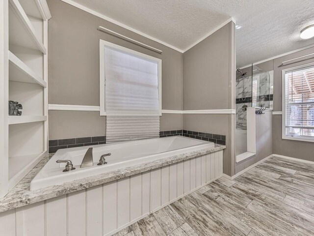 bathroom with hardwood / wood-style flooring, separate shower and tub, ornamental molding, and a textured ceiling