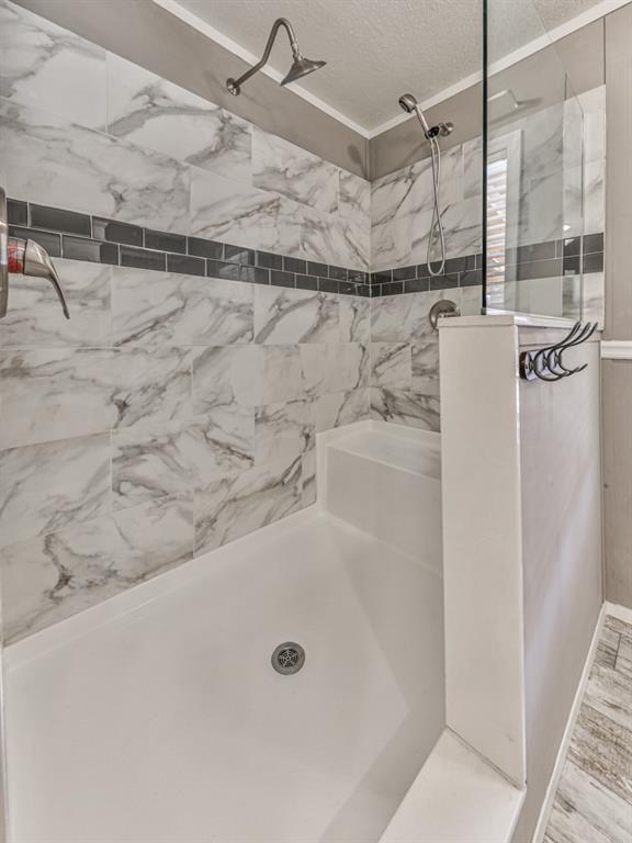 bathroom featuring hardwood / wood-style flooring, tiled shower, and a textured ceiling