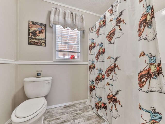 bathroom featuring a shower with shower curtain, toilet, wood-type flooring, and a textured ceiling