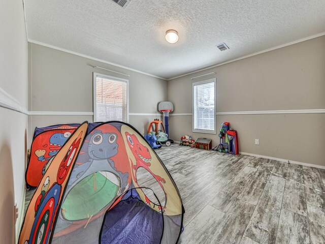 bedroom with hardwood / wood-style flooring, ornamental molding, a textured ceiling, and multiple windows