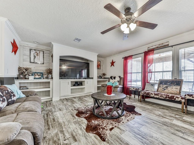 living room featuring ceiling fan, light hardwood / wood-style floors, a textured ceiling, and ornamental molding