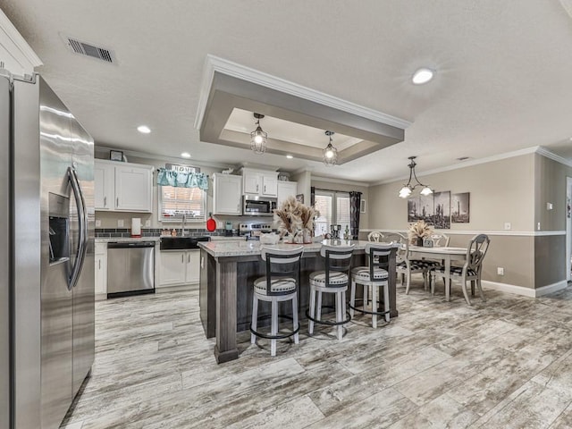 kitchen with white cabinets, a center island, stainless steel appliances, and a wealth of natural light