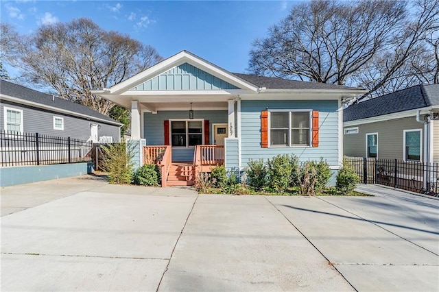 view of front of home with board and batten siding, covered porch, and fence