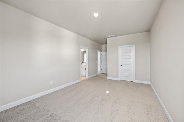 unfurnished bedroom with light carpet, a closet, and ensuite bathroom