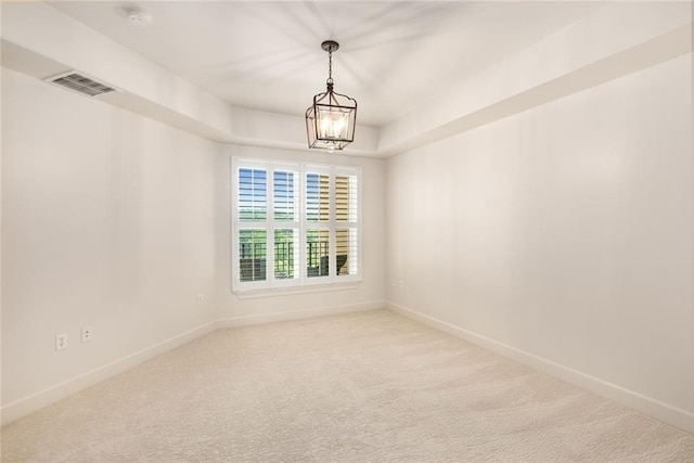 carpeted empty room featuring visible vents, a chandelier, and baseboards
