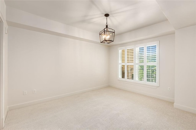 spare room with baseboards, a chandelier, and light carpet