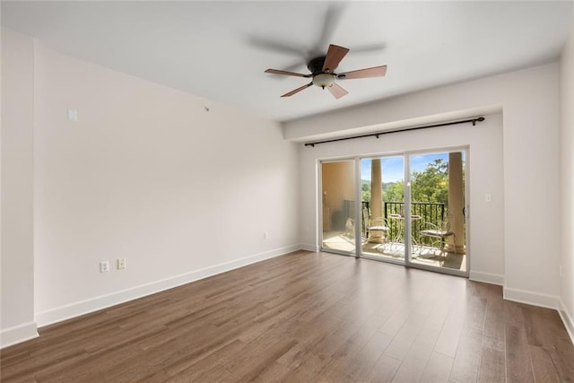 empty room with wood finished floors, a ceiling fan, and baseboards
