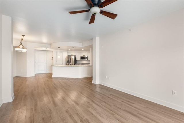 unfurnished living room featuring baseboards, light wood-type flooring, and a ceiling fan