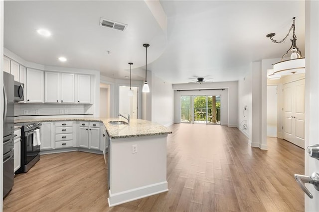kitchen featuring visible vents, open floor plan, stainless steel microwave, black electric range, and a sink
