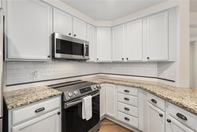 kitchen with appliances with stainless steel finishes, backsplash, and white cabinets
