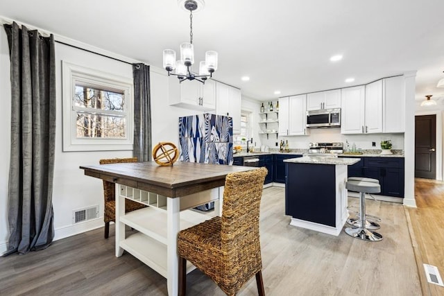 dining area with light hardwood / wood-style floors, sink, and a chandelier