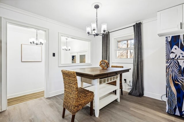 dining area featuring light wood-type flooring, an inviting chandelier, and crown molding